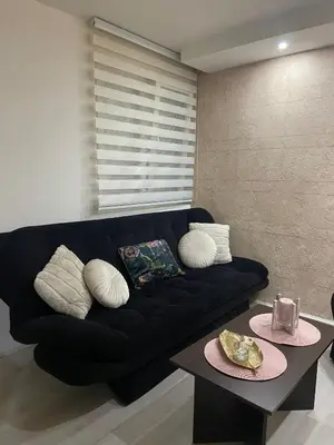 a black couch in a living room with a table at Apartman Rose in Kruševac