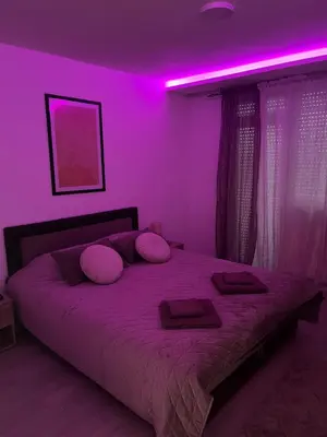 a bedroom with a bed with purple lights on it at Apartman Rose in Kruševac