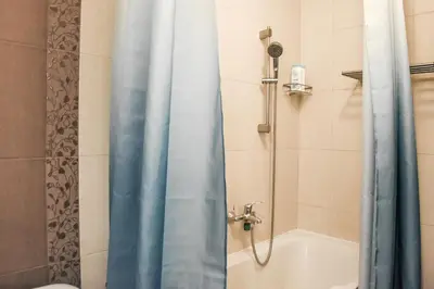 a shower with a blue shower curtain in a bathroom at La Maison in Niš
