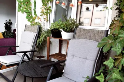two chairs and a table on a porch with plants at La Maison in Niš