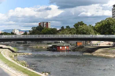 a boat traveling down a river under a bridge at La Maison in Niš