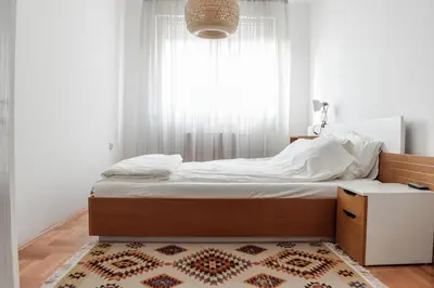 a bed in a bedroom with a window and a rug at La Maison in Niš