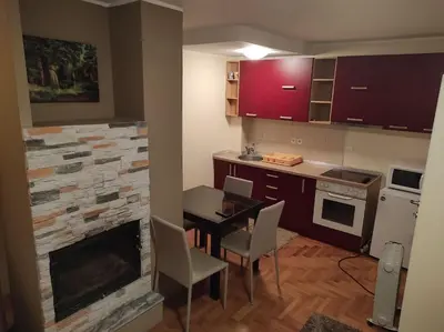 a kitchen with a fireplace and a table and chairs at Apartman Sofija Kraljevi Čardaci in Kopaonik