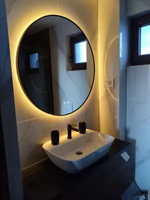 a bathroom with a sink and a round mirror at FlowHouse - cozy place for you. in Kopaonik
