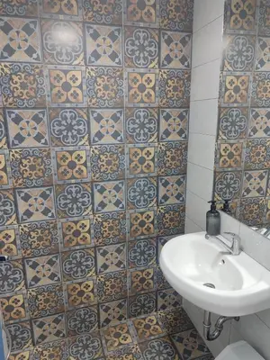 a bathroom with a sink and a tiled wall at Apartmani Hub in Niš