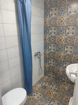 a bathroom with a toilet and a blue shower curtain at Apartmani Hub in Niš