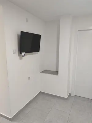 a flat screen tv hanging on a white wall at Apartmani Hub in Niš