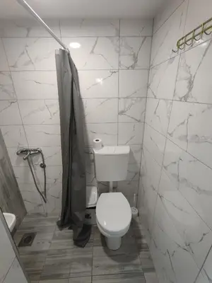 a white bathroom with a toilet and a shower at Apartmani Hub in Niš