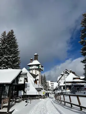 a building covered in snow next to a fence at SKY PEAK KRALJEVI ČARDACI APARTMENT in Kopaonik