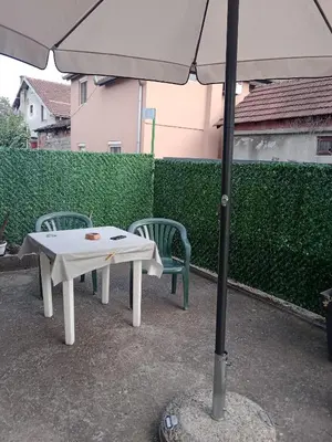 a white table and two chairs under an umbrella at Apartman Nedeljković in Vrnjačka Banja
