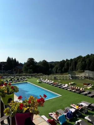 a swimming pool with lawn chairs and people sitting in chairs at Apartman Kiš Kraljevi Čardaci in Kopaonik