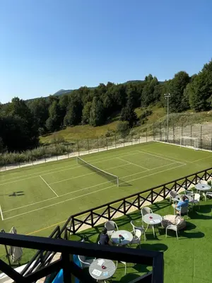 a tennis court with people sitting in chairs on it at Apartman Kiš Kraljevi Čardaci in Kopaonik