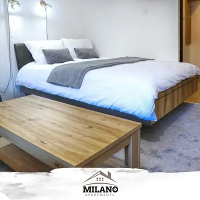 a bedroom with a bed and a wooden table at Milano Apartman **** in Brzeće