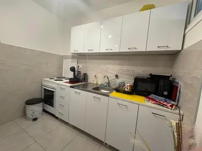 a kitchen with white cabinets and a sink and a microwave at Apartman Slavica in Vrnjačka Banja