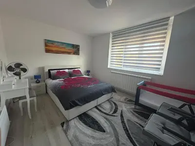 a bedroom with a bed and a desk and a window at Apartman Slavica in Vrnjačka Banja