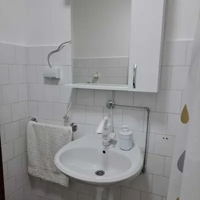 a white bathroom with a sink and a mirror at Apartman Magic in Soko Banja