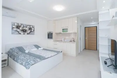 a white bedroom with a bed and a kitchen at Crnjanski Paun L in Jagodina