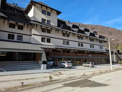 a large building with cars parked in a parking lot at BratSki Apartman - 200m od gondole in Brzeće