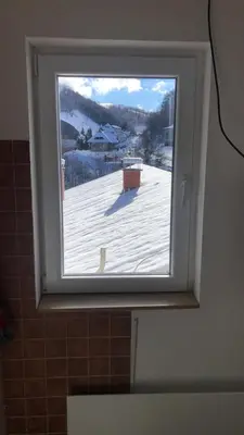 a bathroom window with a view of a snow covered roof at LOVE apartman JeLEna in Brzeće