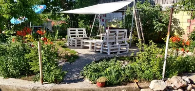 two white chairs and an umbrella in a garden at Apartmani Popović in Knjazevac.