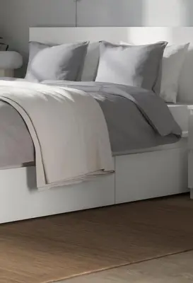 a white bed with grey sheets and pillows at Studio Leone Sunčana Planina in Kopaonik
