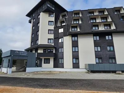 a tall building with a black roof at Studio Leone Sunčana Planina in Kopaonik