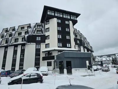 a large building with cars parked in a parking lot at Studio Leone Sunčana Planina in Kopaonik