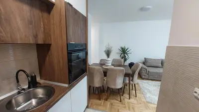 a kitchen with a table and chairs and a couch at Apartman Zapadni Kej M&M in Pirot