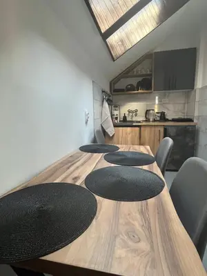 a wooden table with four black chairs and a kitchen at Stanoteka in Vrnjačka Banja