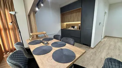 a dining room with a wooden table and chairs at South Apartmani in Vranje