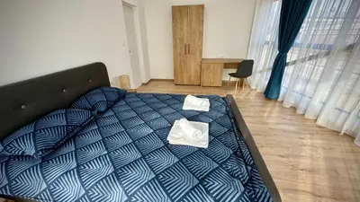 a bed with a blue comforter with a pillow on it at South Apartmani in Vranje
