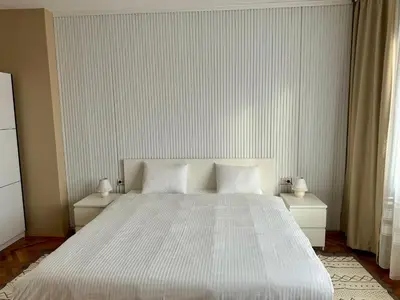 a bedroom with a large white bed with two night stands at Trident Apartments 3 in Niš