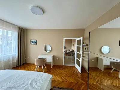 a bedroom with a bed and a desk and a mirror at Trident Apartments 3 in Niš
