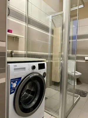 a washing machine in a bathroom with a glass wall at Trident Apartments 3 in Niš