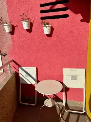 a table and chairs against a pink wall with plants at Trident Apartments 3 in Niš