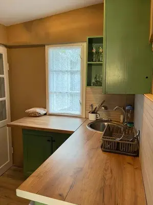 a kitchen with green cabinets and a sink and a window at Villa Lenka Sokobanja in Soko Banja