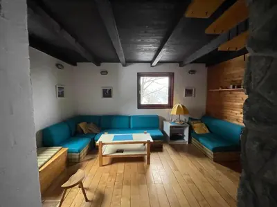 a living room with a blue couch and a table at Planinska kuća Savić, Kopaonik in Kopaonik
