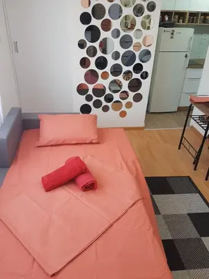 a bed with an orange blanket with a coat on it at Apartman VUK in Pirot