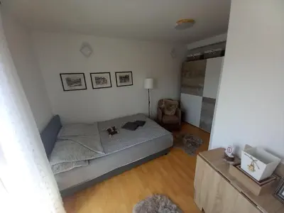 a small bedroom with a bed and a chair at Apartman VUK in Pirot