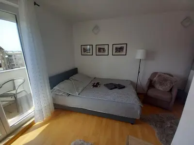 a bedroom with a bed and a chair and a window at Apartman VUK in Pirot