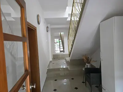 a hallway with a staircase with a chair and a clock at APARTMANSKI SMEŠTAJ SOLARIS kod Aqua Parka Yuth Studio in Soko Banja