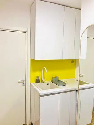 a kitchen with a sink and a yellow accent wall at Happy Sweet Apartment in Niš