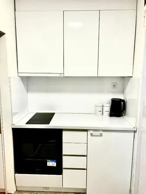 a white kitchen with white cabinets and a black oven at Happy Sweet Apartment in Niš