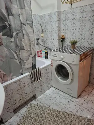 a washing machine in the corner of a bathroom at Nela Apartmani in Niš