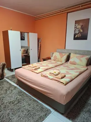 a bedroom with a large bed with orange walls at Nela Apartmani in Niš