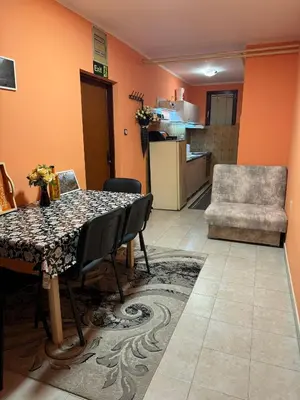 a dining room with a table and chairs and a kitchen at Nela Apartmani in Niš