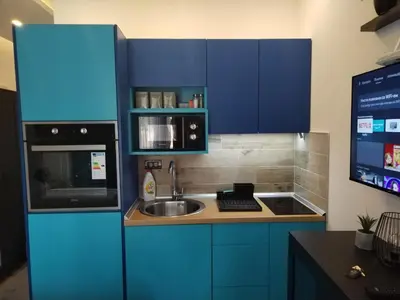 a kitchen with blue cabinets and a sink and a microwave at N Lux 95 Milmari in Kopaonik