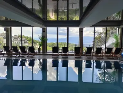 a pool with chairs in a building with windows at N Lux 95 Milmari in Kopaonik