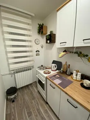 a kitchen with white cabinets and a stove top oven at OLI apartman in Niš