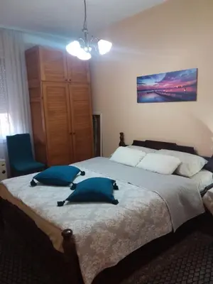 a bedroom with a large bed with two blue pillows at Ikaria in Niš